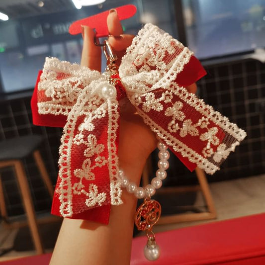 Dragonne de téléphone portable avec nœud en dentelle et fausses perles et coussinet pour cordon